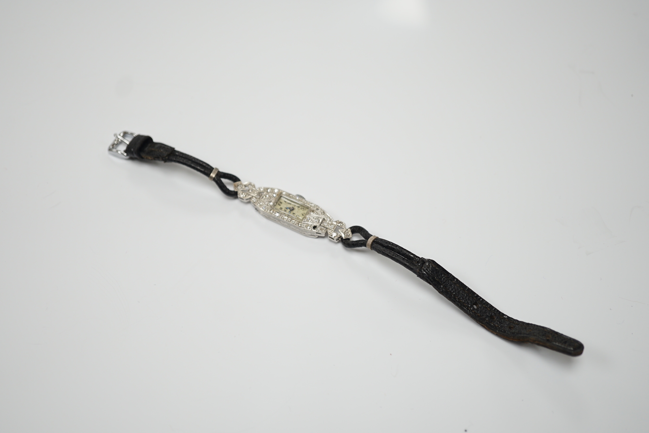 A lady's white metal (engraved platinum) and diamond cluster set manual wind cocktail watch, on a leather strap.
